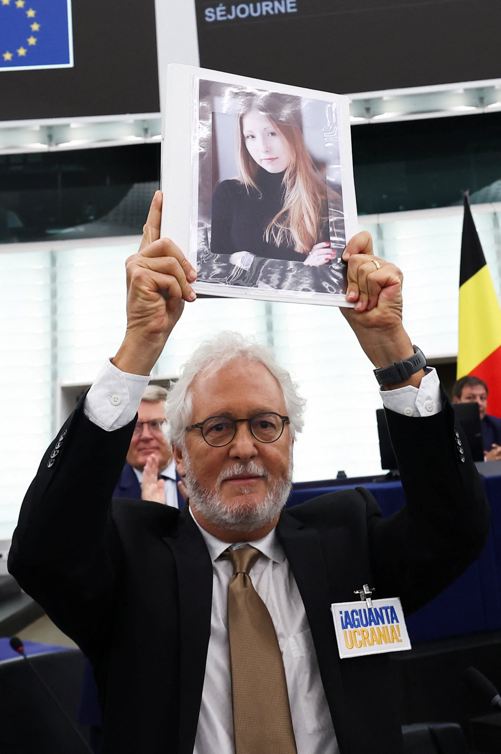 Héctor Abad Faciolince levanta en septiembre del 2023 en el Parlamento europeo una foto de la escritora ucraniana Victoria Amelina, muerta luego de un ataque ruso con misiles en junio de ese año. Abad sobrevivió al ataque. (REUTERS/Yves Herman)