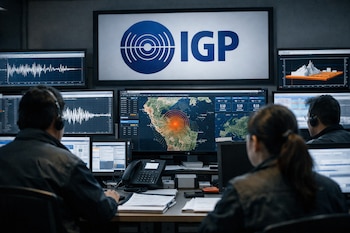 Operadores en centro de monitoreo sísmico del IGP en Perú, viendo pantallas con mapas de actividad y gráficos sísmicos. Logo azul del IGP visible en pantalla superior.