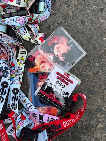 Credenciales de plástico con fotos del grupo BTS y cintas impresas con personajes de BT21 sobre el asfalto