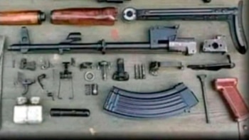 Vista aérea de un rifle desensamblado, mostrando numerosas piezas como el cañón, la culata, el cargador curvo y mecanismos internos, sobre una superficie clara