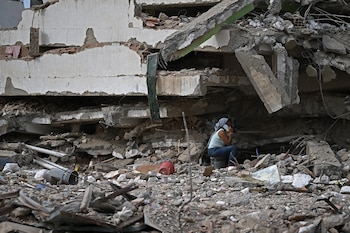 Una mujer habla por teléfono móvil entre los escombros de un edificio derrumbado en Caraballeda, estado de La Guaira, Venezuela, el 9 de julio de 2026 (Raul ARBOLEDA/AFP)