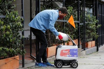 Un hombre con una máscara facial coloca un paquete dentro de un robot de entrega de la compañía colombiana Rappi, en medio del brote de la enfermedad del coronavirus en Medellín, Colombia, 17 de abril, 2020. REUTERS / David Estrada