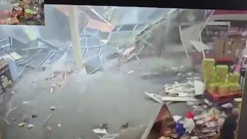 Interior de un local comercial con estanterías metálicas derrumbadas y productos dispersos en el suelo; incluye una vista en miniatura en la esquina superior izquierda
