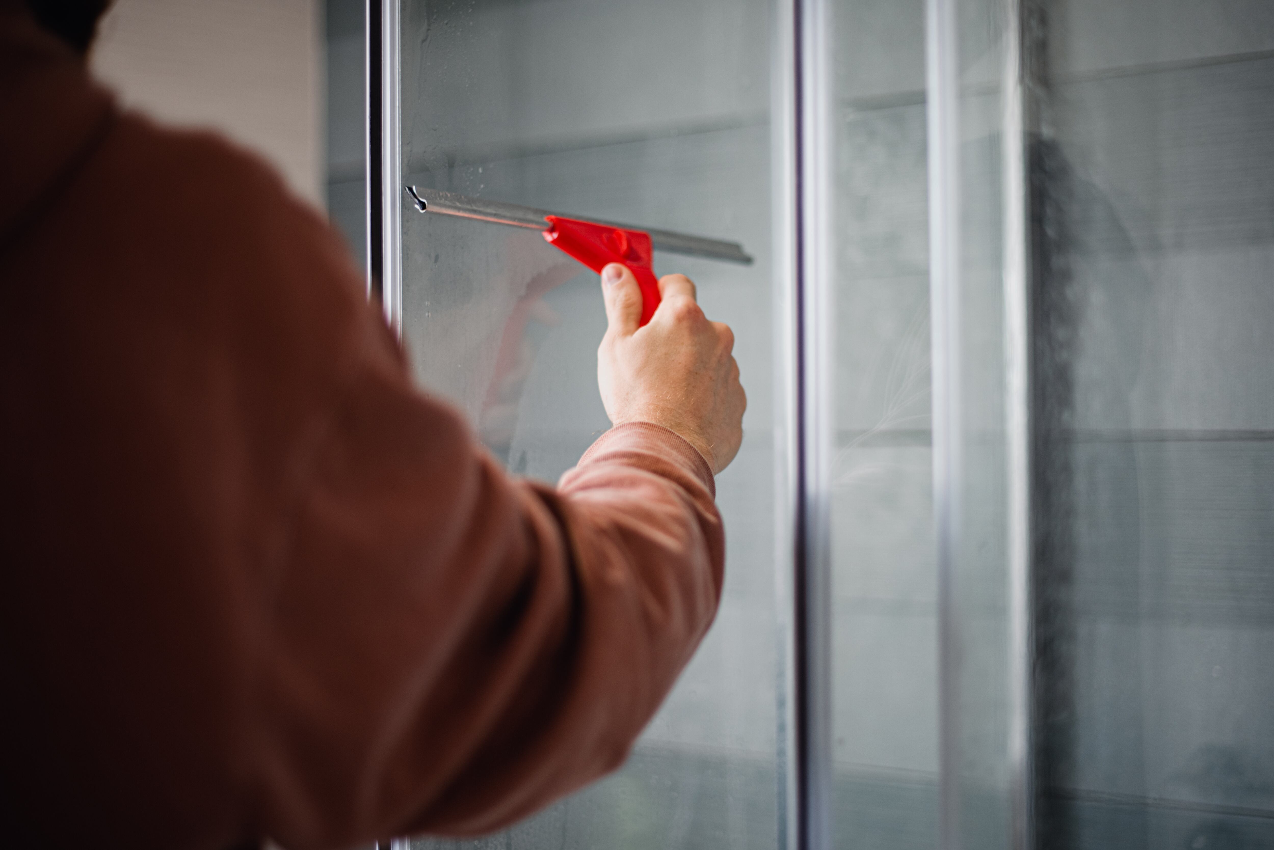Un hombre limpia un cristal. (Adobe Stock)