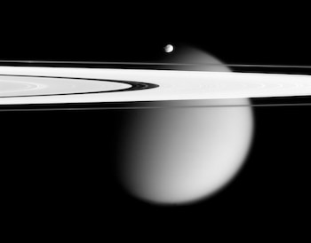 ARCHIVO – En la imagen, tomada por la nave espacial Cassini y proporcionada por la NASA el 12 de marzo de 2006, aparecen dos de las lunas de Saturno, la pequeña Epimeteo y Titán, envuelta en neblina, con los anillos A y F de Saturno extendiéndose por el marco. (NASA vía AP)