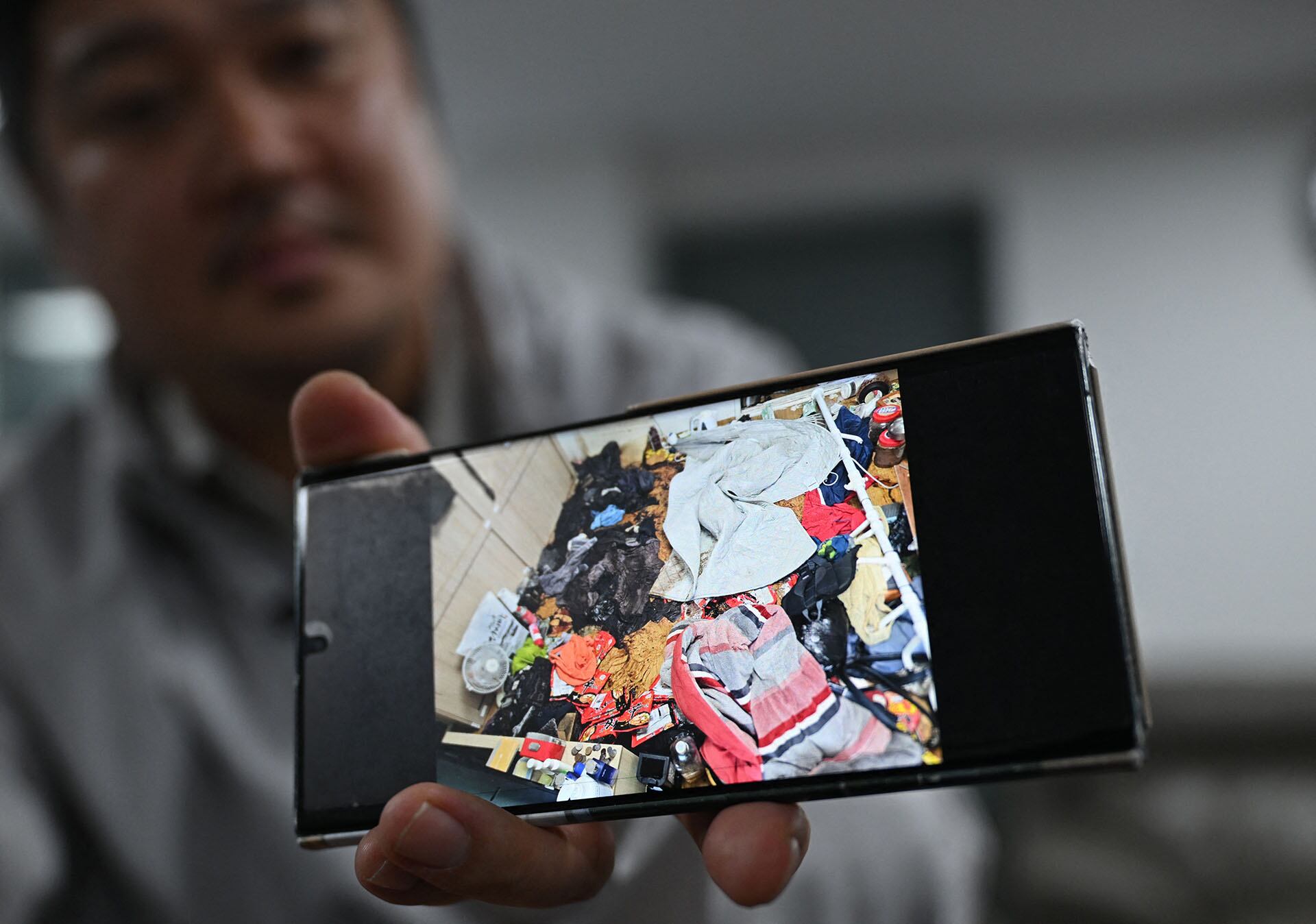Cho Eun-seok, un limpiador que ordena casas tras el fallecimiento de sus ocupantes —a menudo personas que vivían solas—, muestra en su teléfono móvil una fotografía de la habitación desordenada de una persona fallecida durante una entrevista con la AFP en su oficina de Guri. (Foto de Jung Yeon-je / AFP)