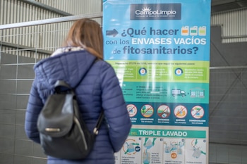 Poster informativo sobre qué hacer con los envases de fitosanitarios vacíos y una persona leyéndolo
