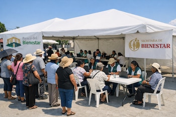 Un módulo de registro exterior con una carpa blanca, personas en fila, mesas, sillas, laptops y personal, con letreros del Banco del Bienestar y Secretaría de Bienestar.