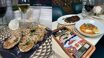 Dos mesas de restaurante. Una muestra mariscos gratinados, limón, copas de vino, botella de agua, rosa. La otra presenta un bistec, puré, copa de vino, vela, menú