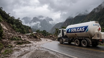 Camión cisterna blanco con el logotipo de Solgas detenido en el asfalto junto a un deslizamiento de tierra, lodo y rocas en la carretera.