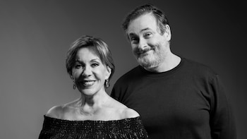 Fotografía en blanco y negro de un hombre con barba y una mujer sonrientes frente a un fondo neutro