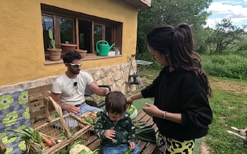 Una familia autosuficiente y sostenible frente a su vivienda ecológica, rodeada de naturaleza pasando el tiempo