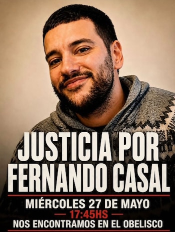 Un hombre sonriente con barba y pelo oscuro viste un suéter gris estampado. El póster anuncia 'Justicia por Fernando Casal' y una marcha en el Obelisco
