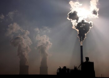 FILE PHOTO: A coal-burning power plant can be seen behind a factory in the city of Baotou in China on October 31, 2010. REUTERS/David Gray/File Photo
