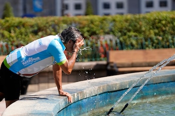 Un ciclista se refresca en la fuente de la Escandalera de Oviedo, este lunes. (Paco Paredes/EFE)