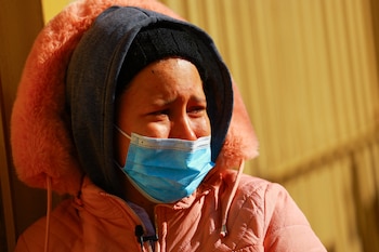 A migrant reacts after her