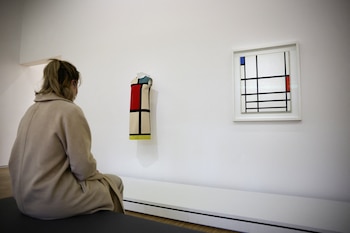 Una mujer observa el vestido "Hommage a Piet Mondrian" del diseñador Yves Saint Laurent, expuesto junto al cuadro "Composition en rouge, bleu et blanc II" de Mondrian, como parte de la exposición "Yves Saint Laurent Aux Musees", en el Centro Pompidou, en París, Francia, el 25 de enero de 2022 (REUTERS/Sarah Meyssonnier)