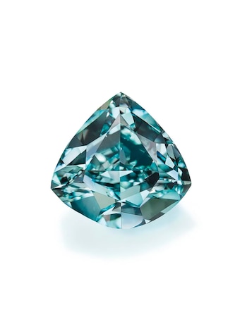 Un diamante azul brillante de talla triangular, con múltiples facetas que reflejan la luz, se muestra sobre un fondo blanco