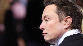 Primer plano del perfil derecho de Elon Musk, con cabello castaño y rostro serio, vistiendo una camisa blanca y chaqueta oscura