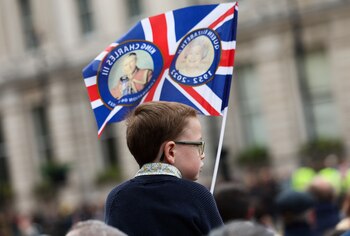 Un niño sostiene una bandera mientras la gente se reúne para ver el desfile de las fuerzas armadas y los veteranos. (REUTERS/Isabel Infantes)