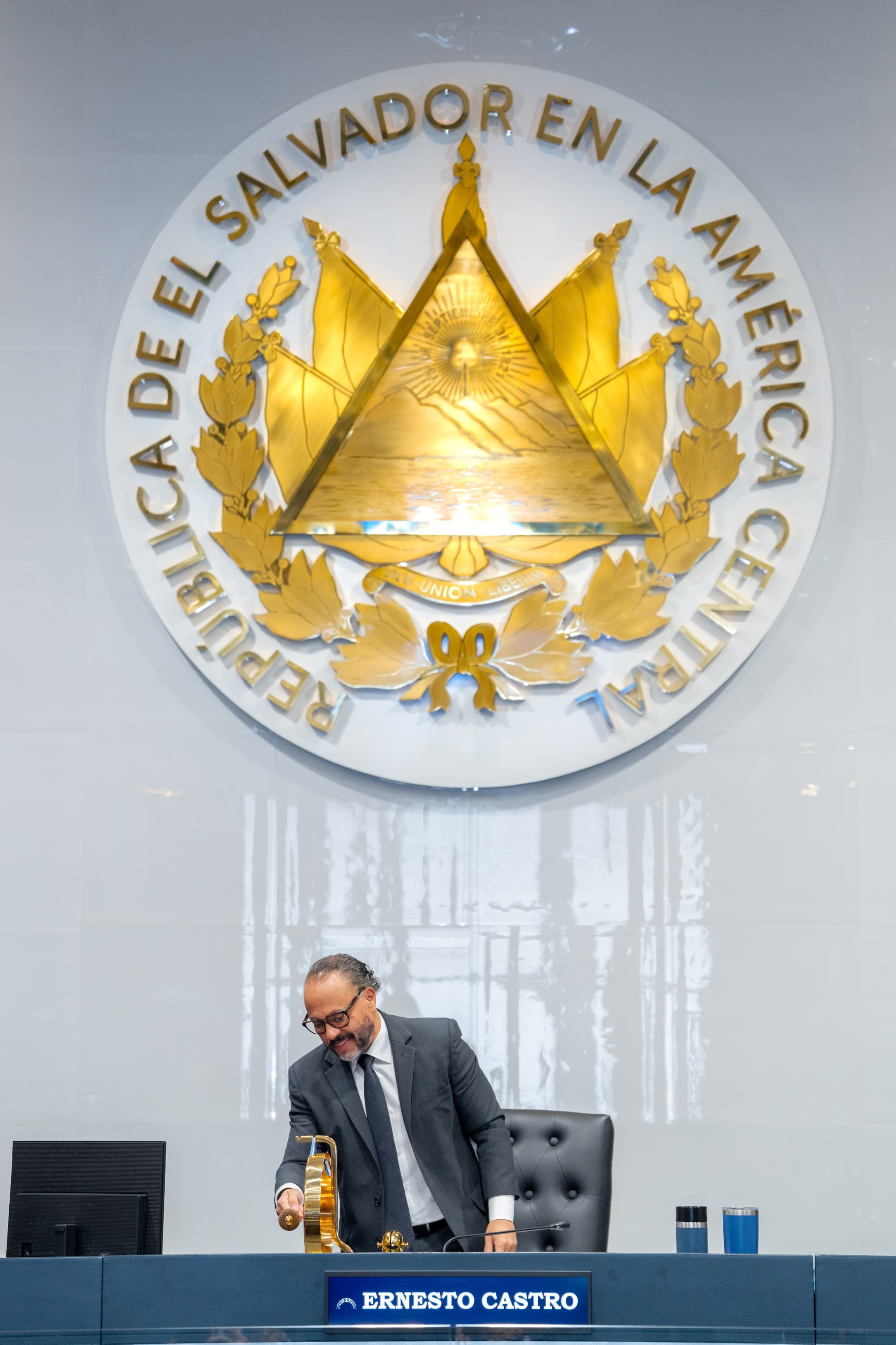 El presidente de la Asamblea Legislativa de El Salvador, Ernesto Castro, dirige la sesión plenaria bajo el escudo nacional, durante la aprobación de la prórroga número 51 del régimen de excepción (Cortesía Ernesto Castro).