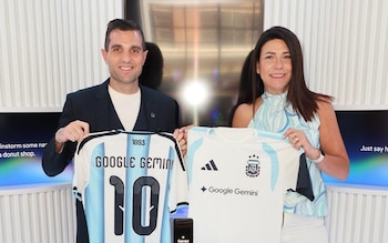 Hombre y mujer sonrientes sostienen camisetas de fútbol. Una celeste y blanca con "Google Gemini" y el número 10. Otra blanca con AFA y "Google Gemini"
