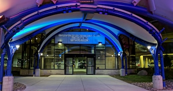 Entrada de cristal con arco metálico e iluminación azul que tiene un letrero del estacionamiento del Aeropuerto de Rochester