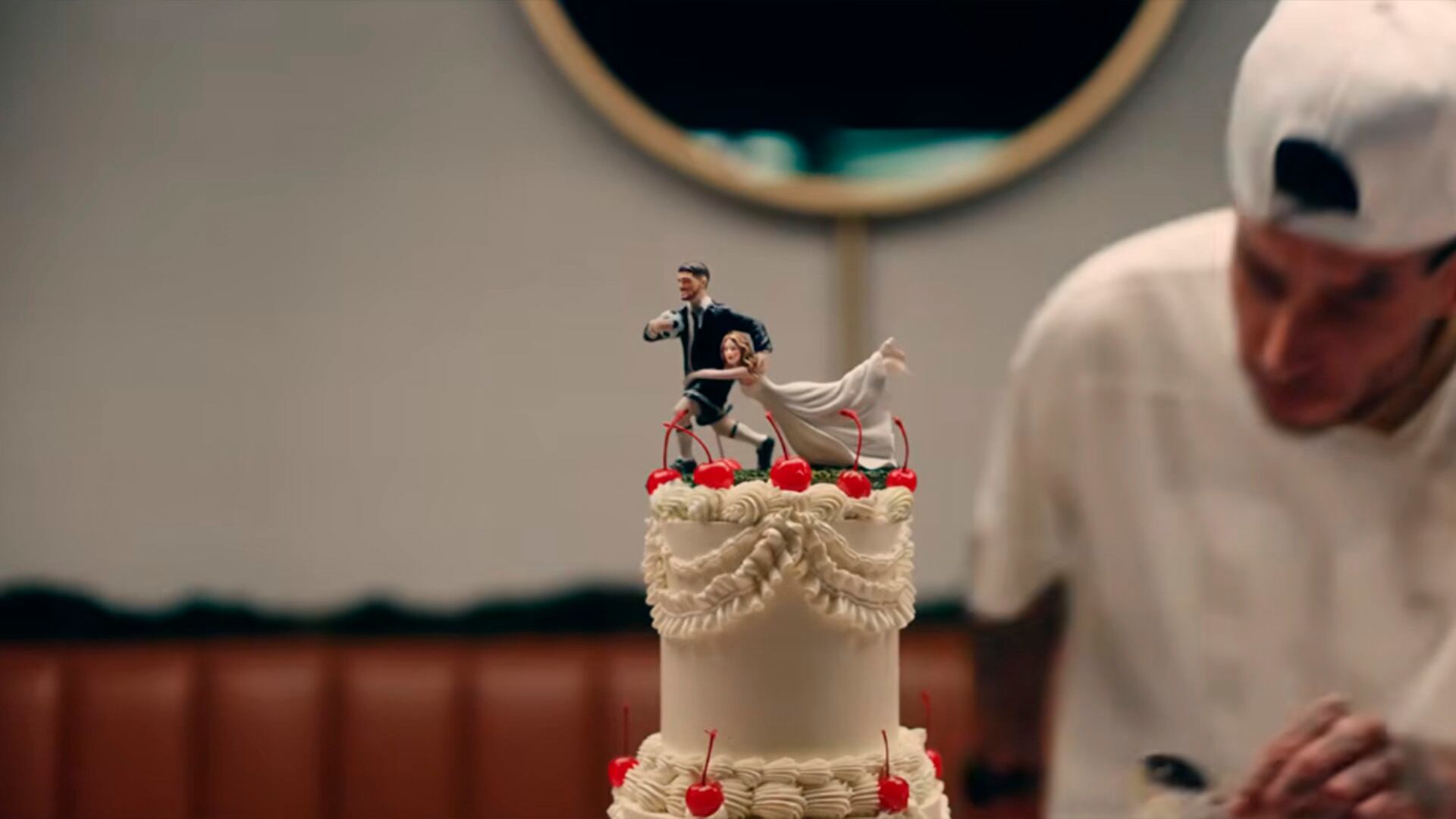 El muñeco masculino de la torta en el videoclip aparece vestido con bermudas y botines, detalles que refuerzan la referencia al fútbol y a Rodrigo De Paul