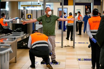 Trabajadores del aeropuerto de Quito (Ecuador) fueron registrados el pasado 1 de junio al revisar a un ciudadano, durante la reapertura de operaciones comerciales de esta terminal aérea. EFE/José Jácome/Archivo