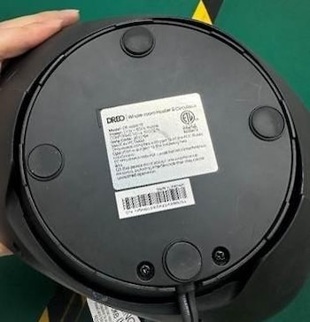 Base circular de plástico negro de un calefactor eléctrico con una etiqueta blanca que presenta especificaciones técnicas y un código de barras