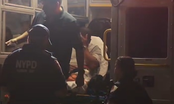 Interior de una ambulancia con personal uniformado de NYPD asistiendo a una persona en una camilla. Hay varias personas más dentro del vehículo
