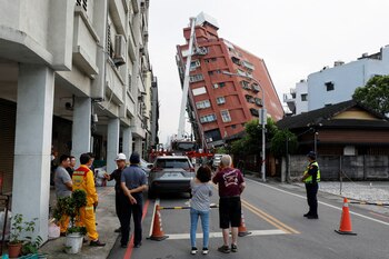 La gente observa mientras los trabajadores realizan operaciones mientras se encuentran en una plataforma elevada de un camión de bomberos en el lugar donde un edificio se derrumbó, tras el terremoto, en Hualien, Taiwán, el 4 de abril de 2024. REUTERS/Carlos García Rawlins