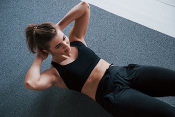 Una mujer haciendo abdominales en el gimnasio (Magnific)