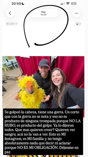 Un hombre y una mujer sonríen, uno al lado del otro, con un niño en el centro vestido con un disfraz de pollo amarillo. Hay cortinas rojas detrás