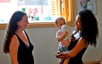 Dachelys Valdés (d), psicóloga cubana, y Hope Bastian (i), antropóloga estadounidense, le dan muestras de cariño a su hijo el pasado lunes 22 de junio de 2020, en La Habana, Cuba. EFE/Ernesto Mastrascusa