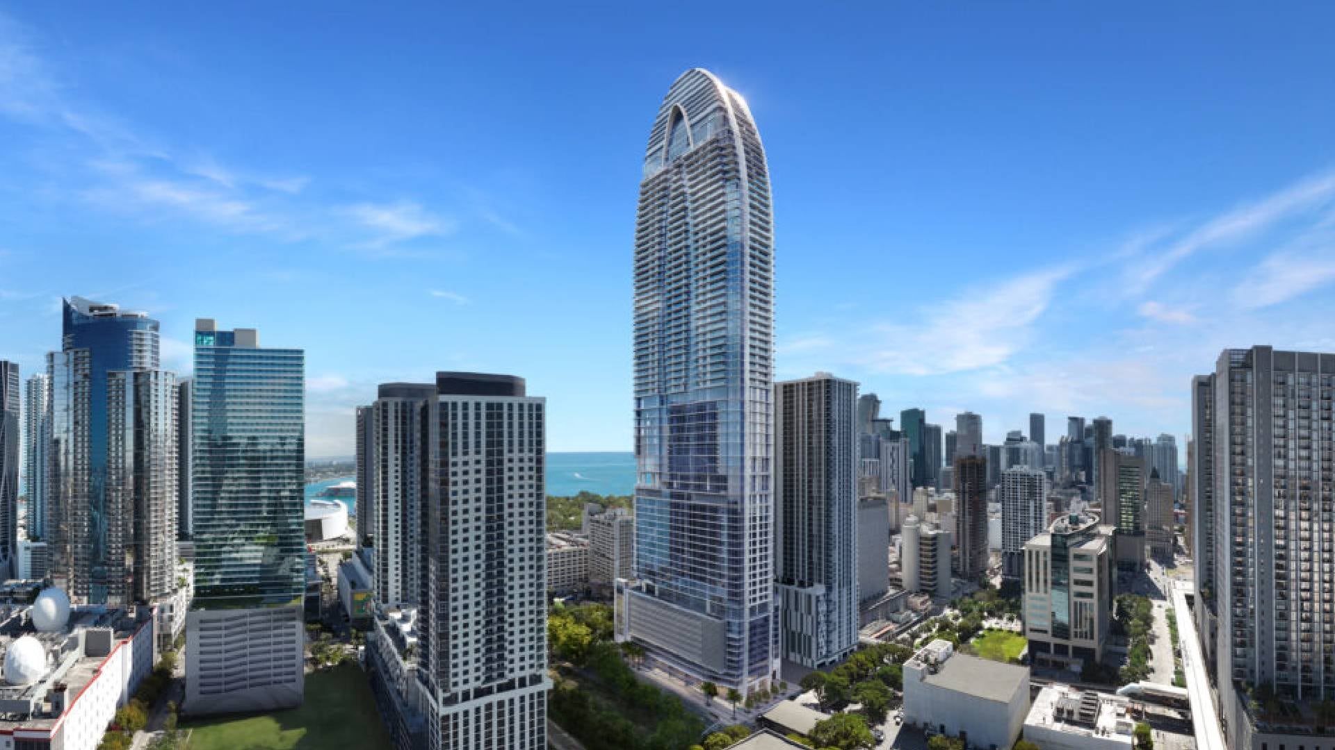 Una vista panorámica muestra la imponente Okan Tower destacando en el horizonte urbano de Miami, rodeada de otros rascacielos y con el océano de fondo bajo un cielo despejado (Okan Group )