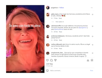 Primer plano de una mujer rubia sonriendo con un vestido oscuro y pendientes rojos, sobre una pantalla con texto 'Te amo con toda mi alma'