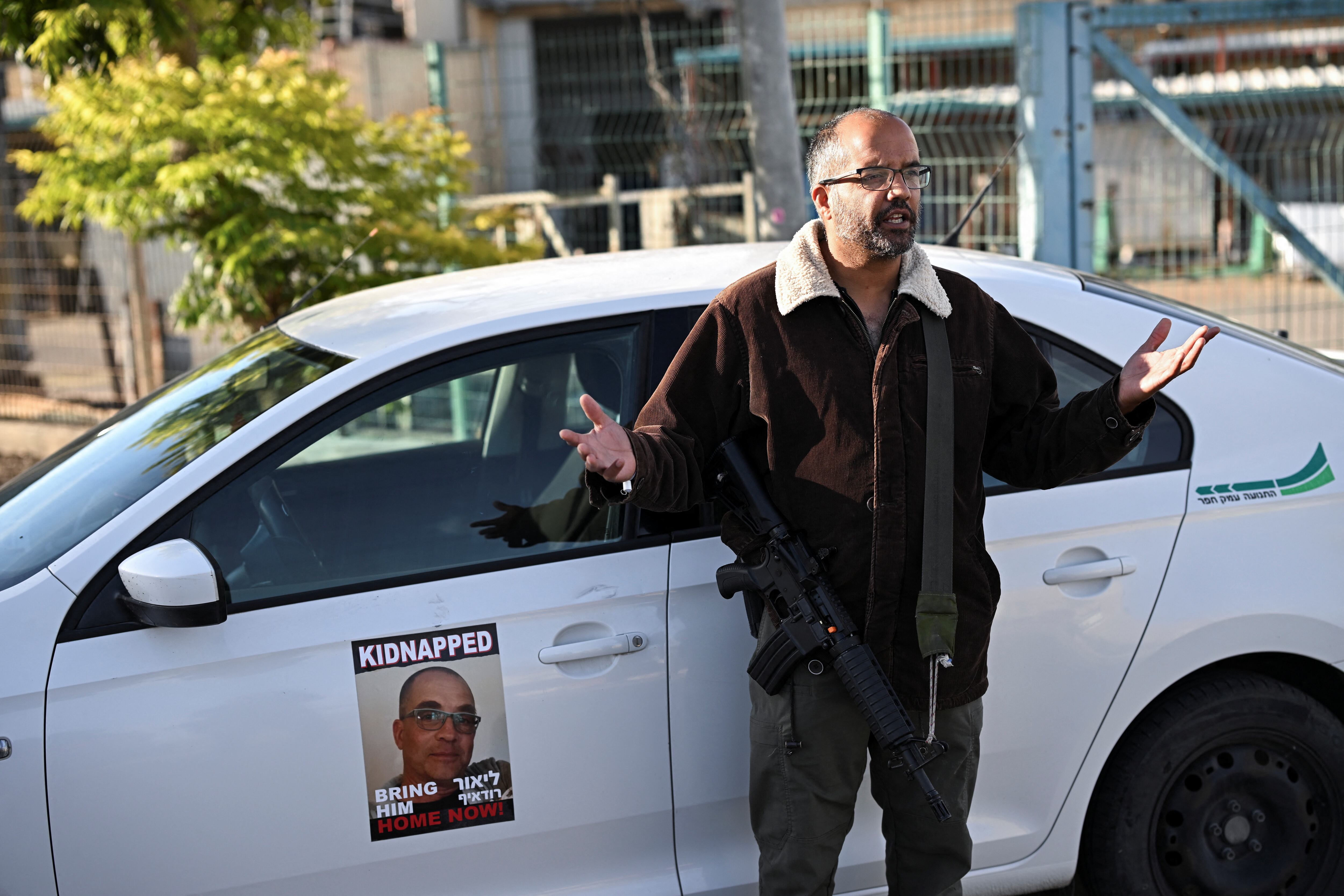 Doron Stamker, hermano de Lior Rudaeff, junto a un auto con la imagen del argentino en Kibbutz, Israel, en febrero de 2024 (REUTERS/Dylan Martinez)