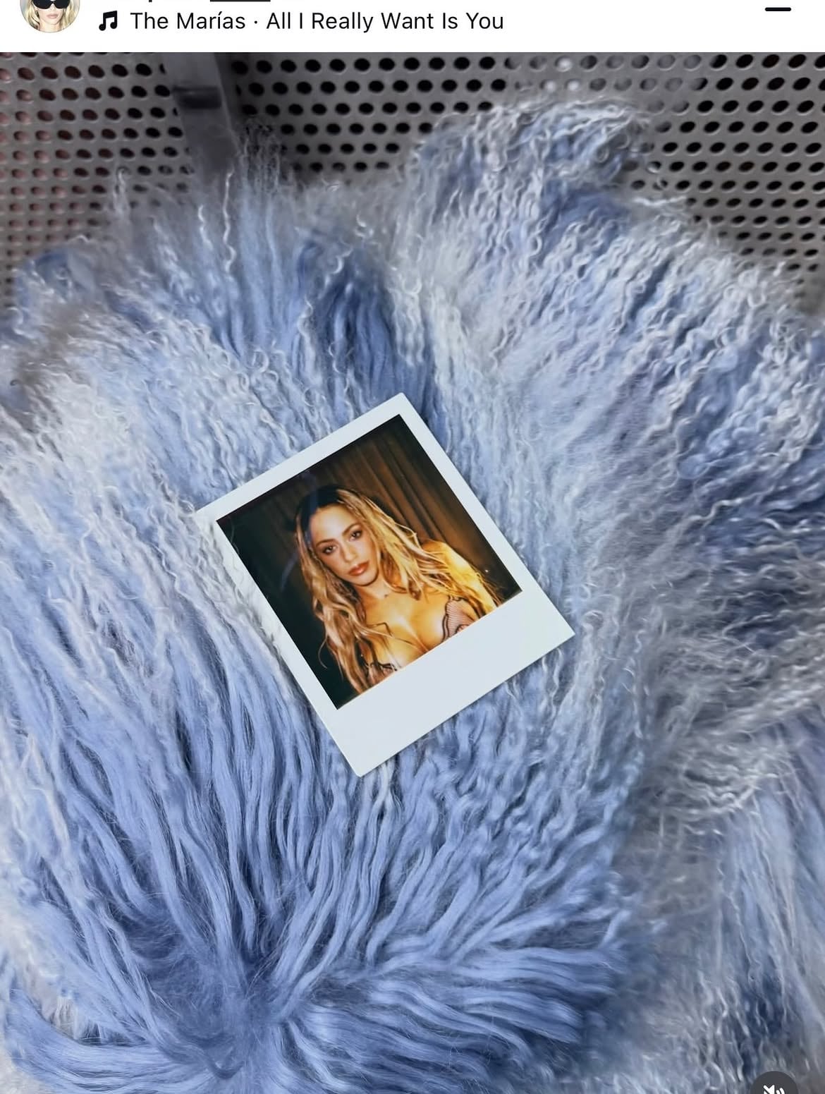 Una fotografía instantánea con el retrato de la cantante Tini reposa sobre una superficie de piel sintética de color azul claro.