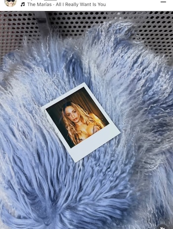 Fotografía instantánea de la cantante Tini colocada sobre un tejido de pelo sintético azul claro