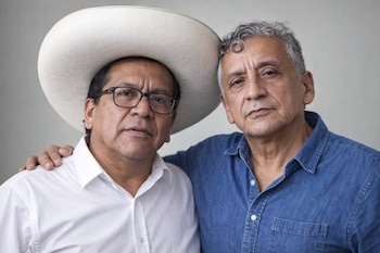 Roberto Sánchez, con sombrero blanco y gafas, posa con Antauro Humala, de cabello gris y camisa de mezclilla azul, en un plano medio.