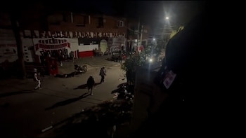 Varias personas caminan de noche por una calle frente a un mural con la frase La Famosa Banda de San Martín y los colores de Chacarita