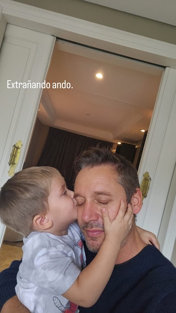 Benjamín Vicuña con ojos cerrados recibe un beso en la mejilla de su hijo Amancio, quien tiene una mano en la cara de su padre