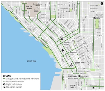 Mapa de la ciudad de Seattle con una red de carriles para bicicletas en verde y futuros tramos punteados, mostrando nombres de calles, estaciones de tren ligero y monorraíl, y el Elliott Bay