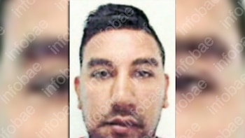 Primer plano del rostro de un hombre joven con cabello oscuro y corto, barba incipiente, mirando directamente a la cámara sobre un fondo claro