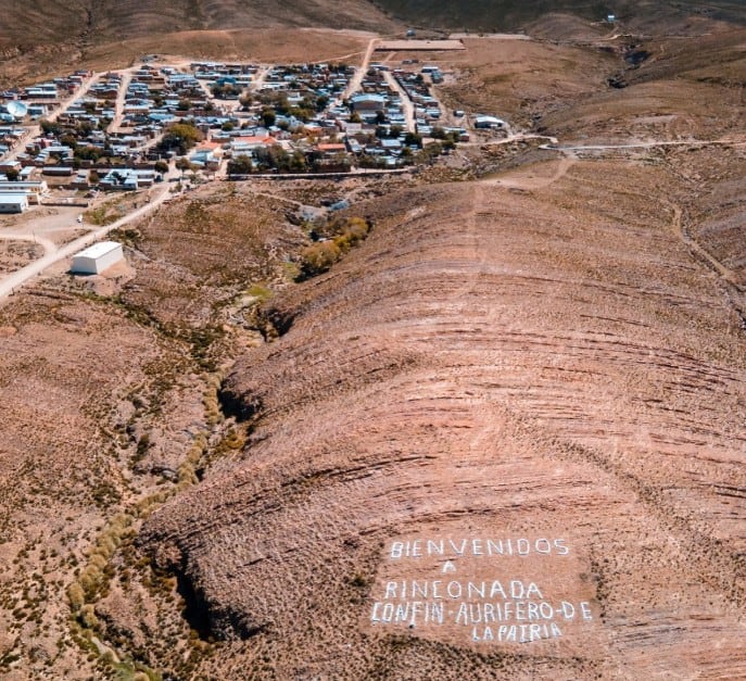 Una vista aérea presenta el poblado de Rinconada en la provincia de Jujuy, junto a una inscripción realizada con piedras sobre la ladera de un cerro.