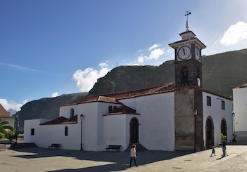 Una iglesia pintada de blanco con la torre de piedra y el tejado que sobresale en conjunto con las paredes.