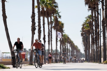 Varias personas recorren en bici el paseo de la Playa de la Patacona durante este jueves en el que la Comunidad Valenciana. (EFE/Manuel Bruque)