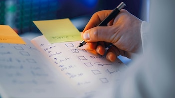 una persona completando un listado de un cuaderno