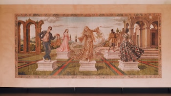 Tapiz rectangular con cinco figuras en pedestales frente a ruinas clásicas y paisaje. Los personajes visten ropa variada, de estilo antiguo y moderno